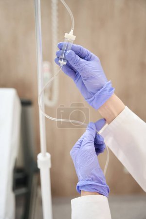 Photo for Close up portrait of hands in gloves of medicine worker is preparing dropper for patient in the hospital - Royalty Free Image