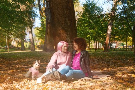 Photo for Young woman and her serious female companion sitting on ground and talking - Royalty Free Image