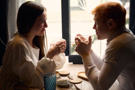 Foto de El tipo pelirrojo se comunica con una novia mientras toma el té, una pareja descansa en una mesa en un café - Imagen libre de derechos