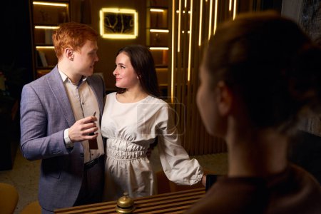 Téléchargez les photos : Heureux jeunes mariés s'enregistrent dans un hôtel démocratique, le couple se tient à la réception - en image libre de droit