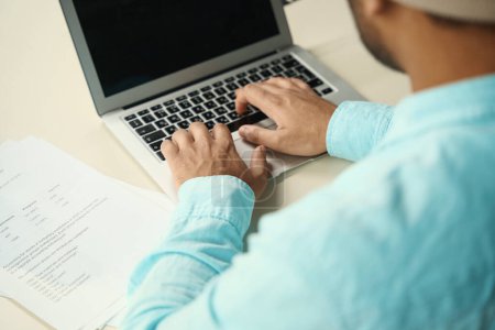 Foto de Primer plano de la foto del hombre sentado en el escritorio y el trabajo en la computadora cerca de los documentos en la oficina - Imagen libre de derechos
