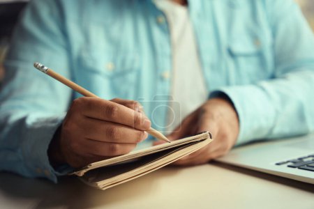 Photo for Man sitting on chair at table and drawing in notebook in the business center - Royalty Free Image
