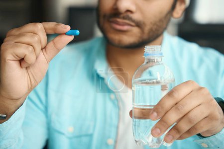 Téléchargez les photos : Homme tenant pilule et bouteille d'eau dans sa main dans le bureau - en image libre de droit