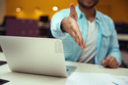 Téléchargez les photos : Homme assis à table devant un ordinateur portable et donne sa main dans le centre d'affaires - en image libre de droit