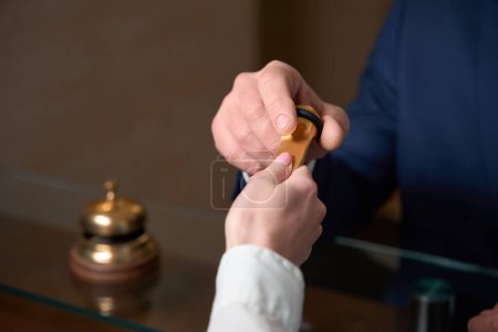 Téléchargez les photos : Homme en tenue de travail debout près de la réception, administrateur debout près et donnant des clés - en image libre de droit