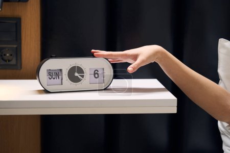Foto de Despertador electrónico muestra la hora, fecha y día de la semana, la mujer apaga el despertador - Imagen libre de derechos