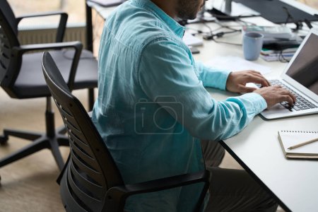 Téléchargez les photos : Jeune homme assis à table et tapant sur l'ordinateur au travail dans le centre d'affaires - en image libre de droit