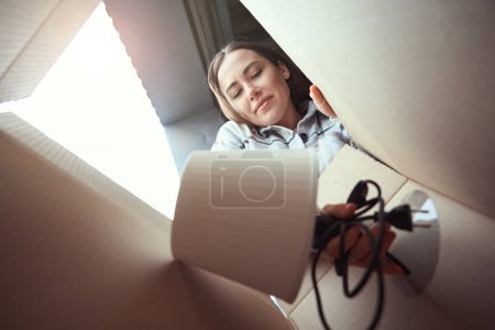 Photo for Low view of pleased woman stacking subject in the cardboard box - Royalty Free Image