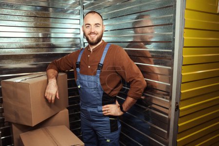 Photo for Happy grown man standing in the storage room leaning on a cardboard box - Royalty Free Image
