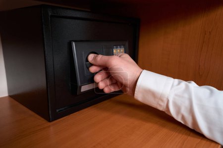 Foto de Hombre adulto girando la manija de la cerradura en la puerta segura en el hotel - Imagen libre de derechos