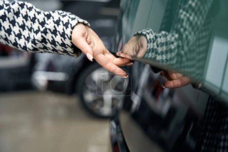Photo for Customer opens the door of a modern car, a woman in stylish clothes and with well-groomed hands - Royalty Free Image