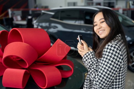 Téléchargez les photos : Jeune asiatique femelle stands avec des clés de voiture en face de la voiture avec cadeau arc - en image libre de droit