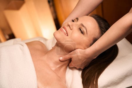 Téléchargez les photos : Chiropracteur mains étirant les muscles du cou du client souriant spa pendant la séance d'ostéopathie - en image libre de droit