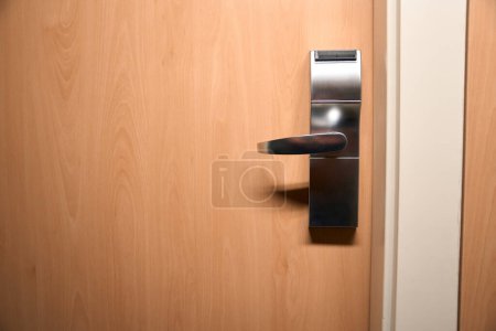 Téléchargez les photos : Photo rapprochée de porte fermée en bois avec poignée métallique. Enregistrement dans la chambre d'hôtel - en image libre de droit