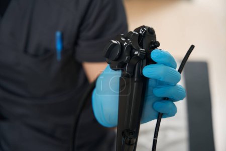Téléchargez les photos : Photo recadrée de l'endoscopiste tenant l'endoscope avec tube d'insertion avec main gantée - en image libre de droit