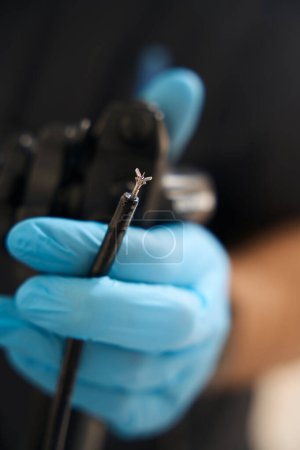 Téléchargez les photos : Gros plan de la main diagnosticienne dans un gant nitrile jetable tenant des pinces de biopsie endoscopique avec aiguille - en image libre de droit