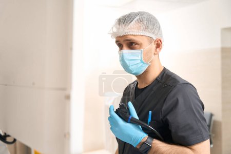 Foto de Retrato de cintura hacia arriba del diagnosticador que sostiene el endoscopio con la mano enguantada mientras mira la pantalla del monitor durante la endoscopia - Imagen libre de derechos