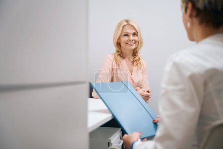 Foto de Una buena dama visita a un ginecólogo en un centro de cosmetología. Mujer sonriendo tiernamente al doctor - Imagen libre de derechos