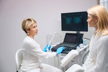 Téléchargez les photos : Médecin gynécologue se prépare à diagnostiquer le patient à l'aide d'un dispositif d'échographie vaginale. Le médecin commence le diagnostic des organes pelviens - en image libre de droit