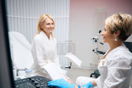 Téléchargez les photos : Photo d'une femme une patiente assise sur une chaise gynécologique chez le médecin - en image libre de droit