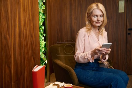 Foto de Mujer cliente del centro de cosmetología sonriendo mira a su teléfono inteligente. Foto de una mujer bonita que usa un teléfono inteligente - Imagen libre de derechos