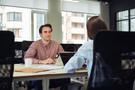 Téléchargez les photos : Travailleur d'entreprise avec ordinateur portable assis devant son collègue au bureau - en image libre de droit