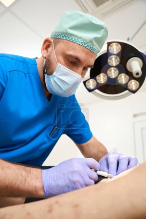 Photo for Surgeon phlebologist making injections to patient for the treatment of network of veins on legs. Man in doctor office - Royalty Free Image