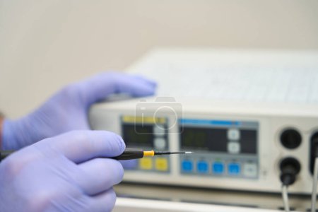 Photo for Hands of a doctor adjusting a radio wave knife apparatus for removing moles and papillomas - Royalty Free Image