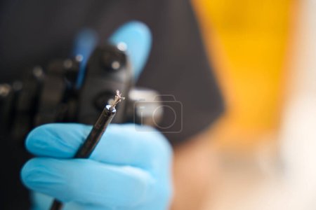 Téléchargez les photos : Gros plan de la main du médecin dans un gant en nitrile tenant une sonde endoscopique avec pinces à biopsie - en image libre de droit