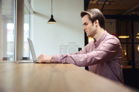 Photo for Side view of serious concentrated young office worker looking at computer monitor - Royalty Free Image