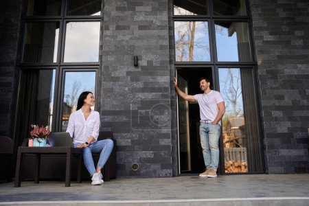 Téléchargez les photos : Jeune homme et une fille parlent sur le porche près de leur maison - en image libre de droit
