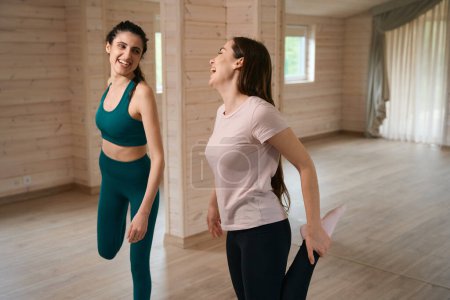 Photo for Smiling female friends in tracksuits looking at each other and getting ready to doing in for sports - Royalty Free Image