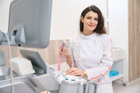 Foto de Médico sonriente en bata blanca trabajando en el equipo y el dispositivo de retención en el gabinete en el hospital - Imagen libre de derechos