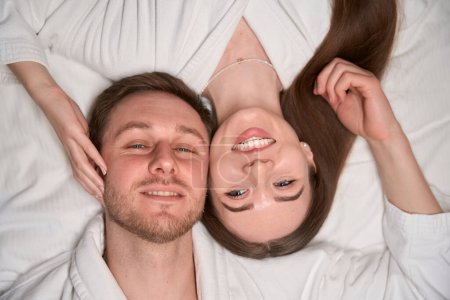 Téléchargez les photos : Vue du dessus de la jeune femme souriante et homme heureux couché sur le lit - en image libre de droit
