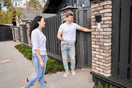 Photo for Smiling guy invites girlfriend to the open door of a new house - Royalty Free Image