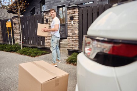 Téléchargez les photos : L'homme porte des boîtes avec des choses à la maison lors du déménagement - en image libre de droit