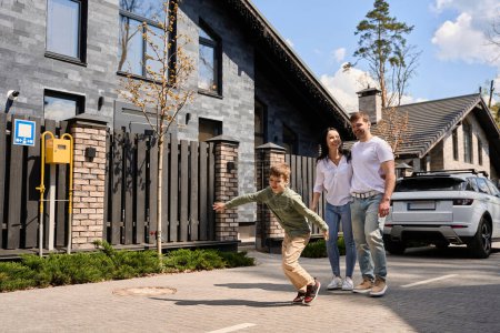 Photo for Young family happily walks down the street with beautiful houses around - Royalty Free Image