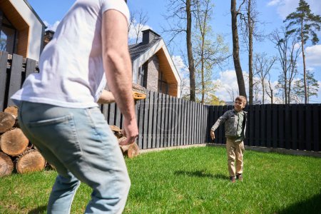 Photo for Child has fun playing with dad on a green lawn near the house - Royalty Free Image