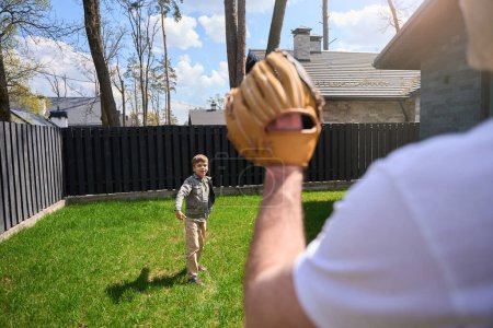 Téléchargez les photos : Homme caucasien avec un gant de baseball joue avec un enfant sur son territoire - en image libre de droit