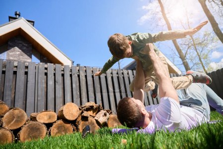 Photo for Little boy and father have fun in front in the yard of their house - Royalty Free Image