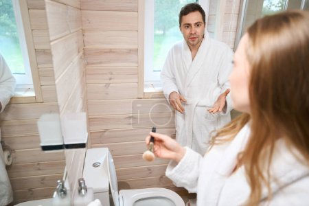 Téléchargez les photos : Jeune couple dans la salle de bain parlant tout en se tenant dans la salle de bain - en image libre de droit