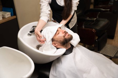 Téléchargez les photos : Artisanat sèche et masse la tête du client avec une serviette douce, le mâle est situé à un évier spécial - en image libre de droit