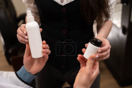 Photo for Man and a woman are holding jars with care products in their hands, people are in a hairdresser - Royalty Free Image
