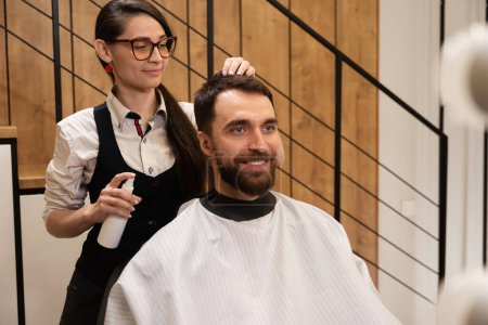 Foto de Peluquería en la peluquería se encarga del cabello de un hombre, el cliente se encuentra en una silla cómoda - Imagen libre de derechos