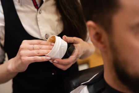 Téléchargez les photos : Artisanat dans un salon de coiffure utilise un outil de coiffage dans son travail, le client est situé dans une chaise de coiffeur - en image libre de droit