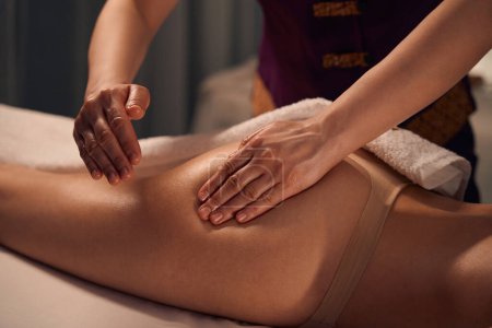Photo for Cropped photo of client lying prone while masseuse palm pressing on her glute - Royalty Free Image