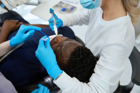 Foto de Estomatóloga de vista superior inyectando anestésico con jeringa estéril a paciente masculino con dientes problemáticos y doloridos - Imagen libre de derechos