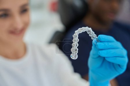 Foto de Técnico dental sosteniendo frenos invisibles, o alineadores transparentes, piezas de plástico extraíbles que se ajustan sobre los dientes del paciente y se pueden quitar durante un par de horas al día - Imagen libre de derechos