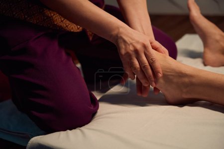 Photo for Cropped photo of massotherapist stretching top of female foot using both hands - Royalty Free Image