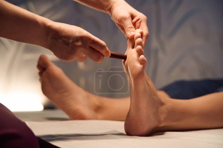 Photo for Cropped photo of qualified reflexologist stimulating reflex point on client sole with reflexology stick - Royalty Free Image
